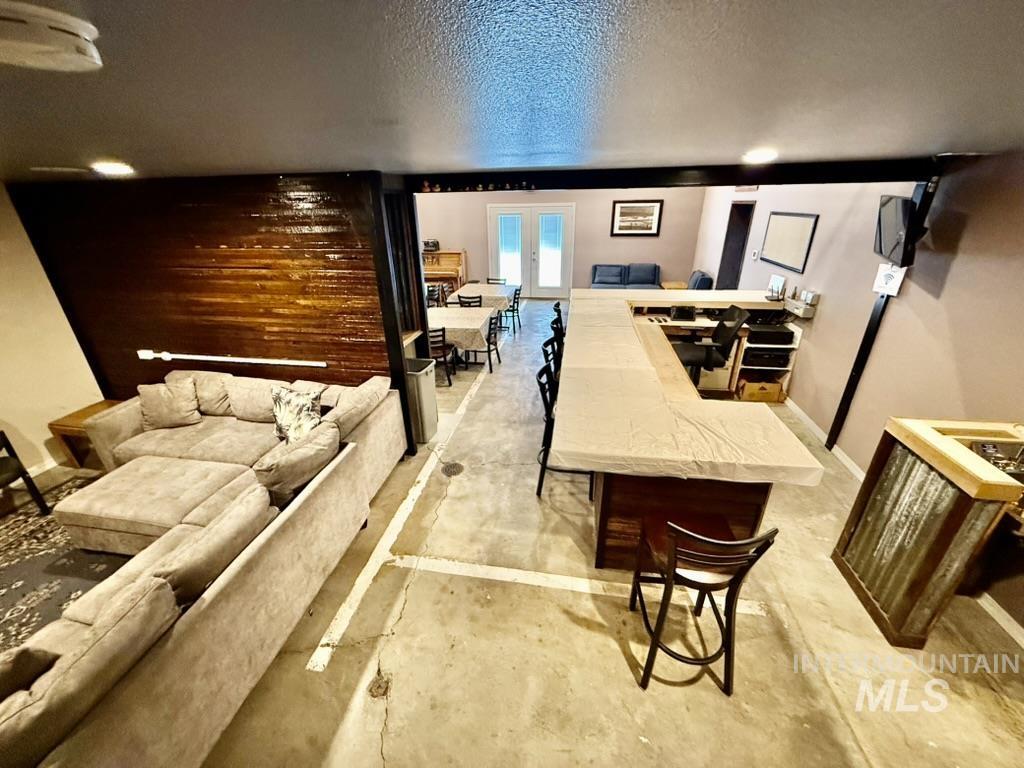 Living room with concrete floors, a textured ceiling, and french doors