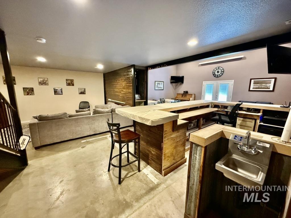 Bar featuring unfinished concrete flooring, stairway, and recessed lighting