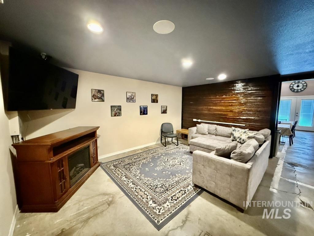 Living area featuring finished concrete floors, wooden walls, recessed lighting, and a fireplace