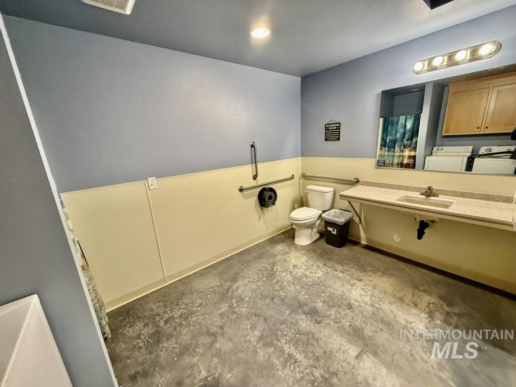 Bathroom with concrete flooring, washing machine and dryer, and vanity