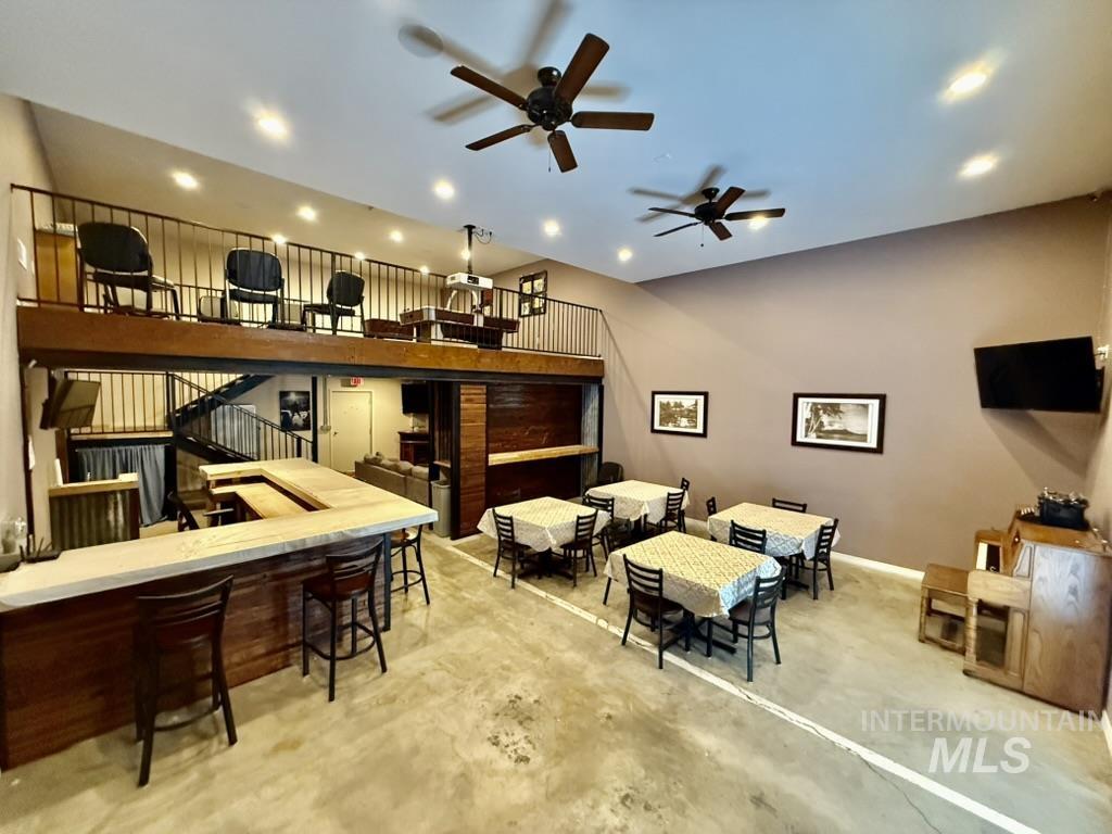Living area featuring a ceiling fan and unfinished concrete flooring