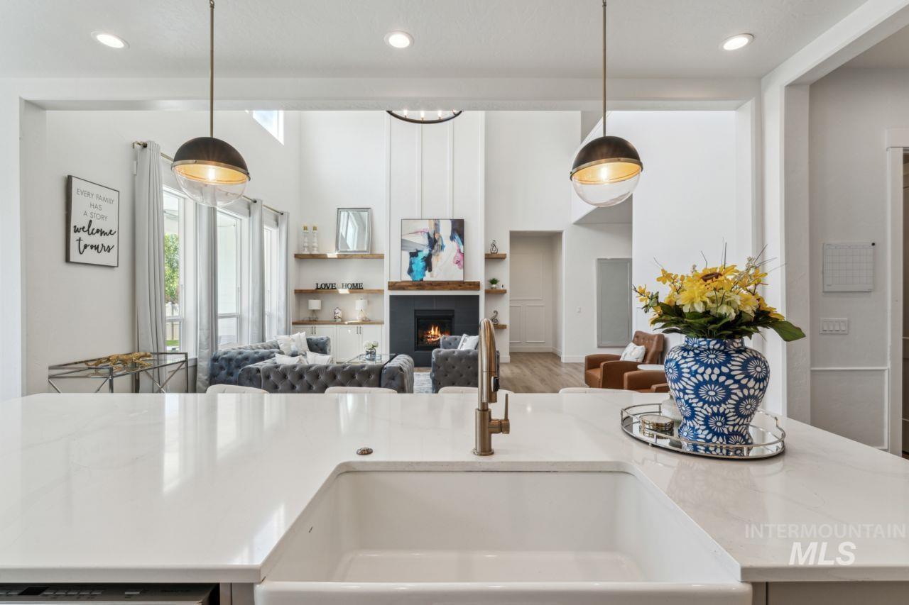 Kitchen featuring open floor plan, recessed lighting, a lit fireplace, light stone countertops, and hanging light fixtures