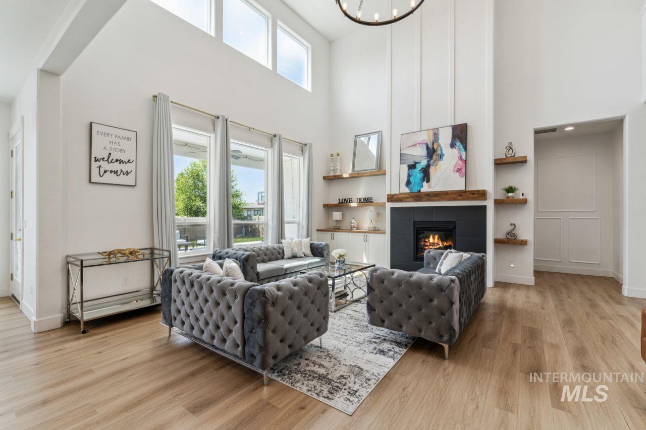 Living area featuring a tile fireplace, light wood-style floors, and a towering ceiling