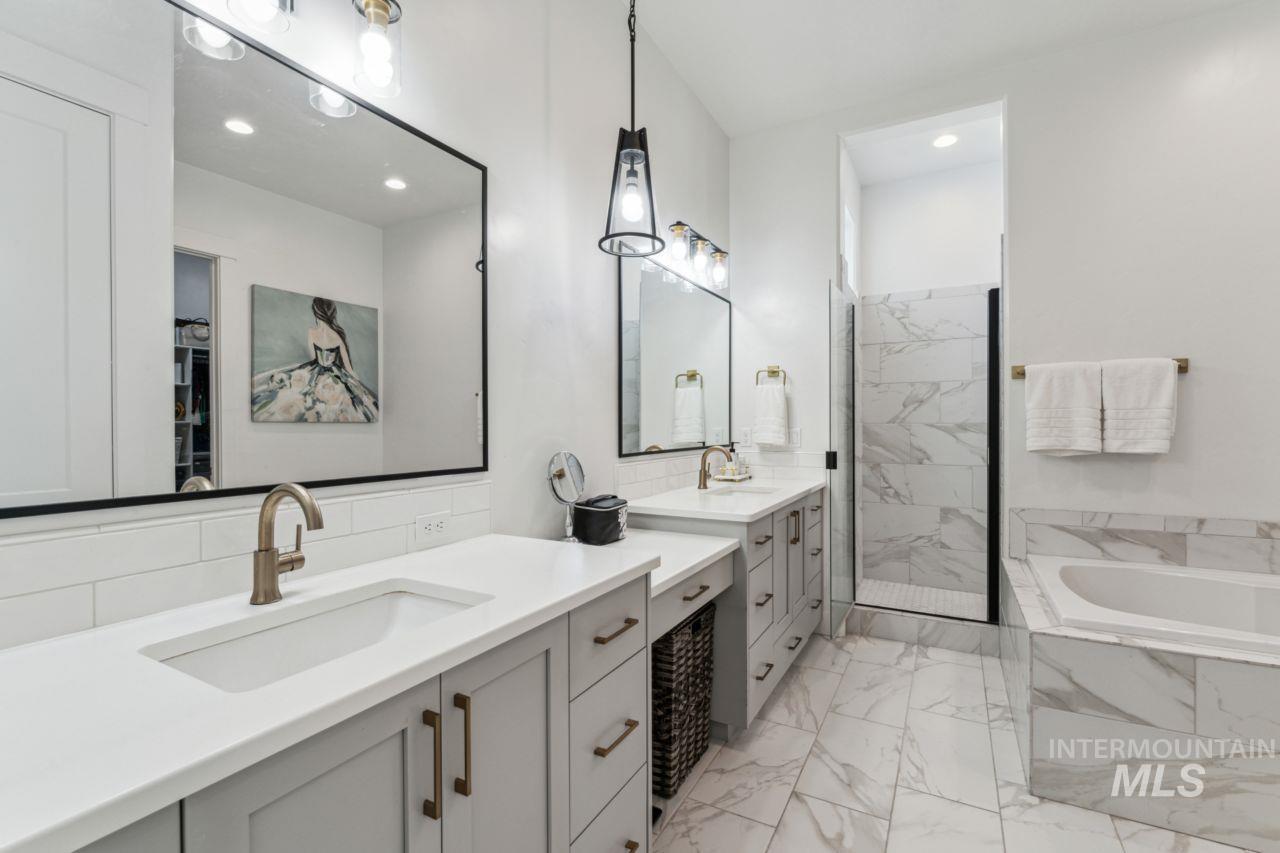 Bathroom featuring a bath, marble look tile flooring, vanity, a marble finish shower, and recessed lighting