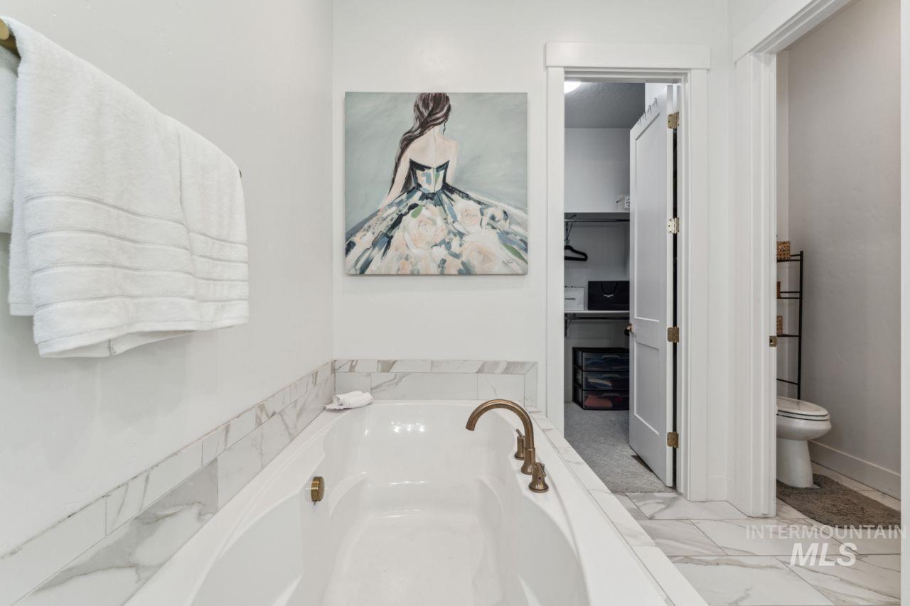 Full bathroom featuring a garden tub and marble finish floors