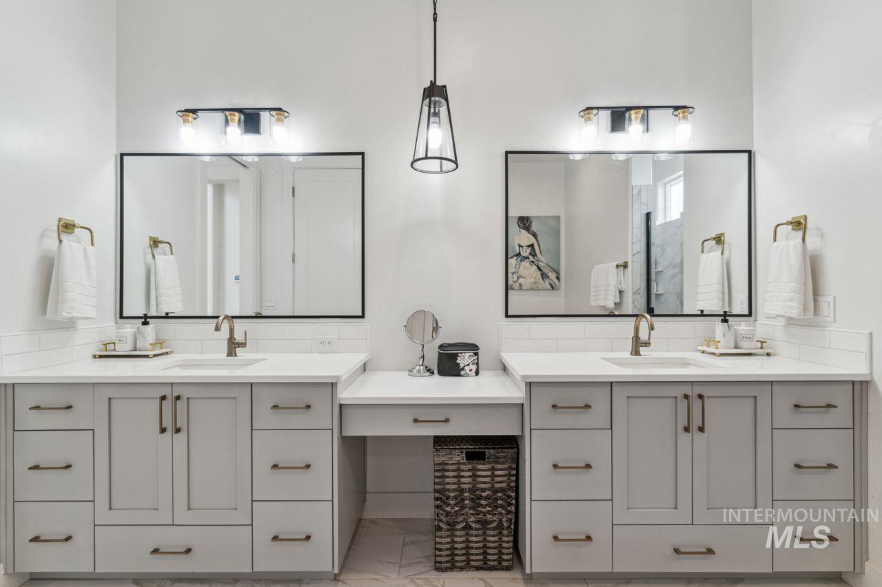Bathroom featuring marble finish flooring, two vanities, and backsplash