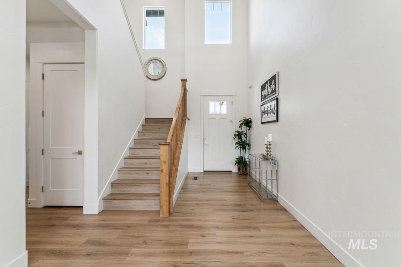 Foyer entrance featuring light wood-style flooring, stairs, and a towering ceiling