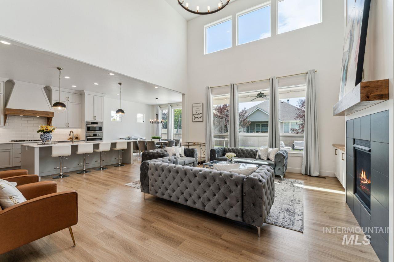 Living room with a chandelier, light wood-style flooring, a fireplace, and a ceiling fan