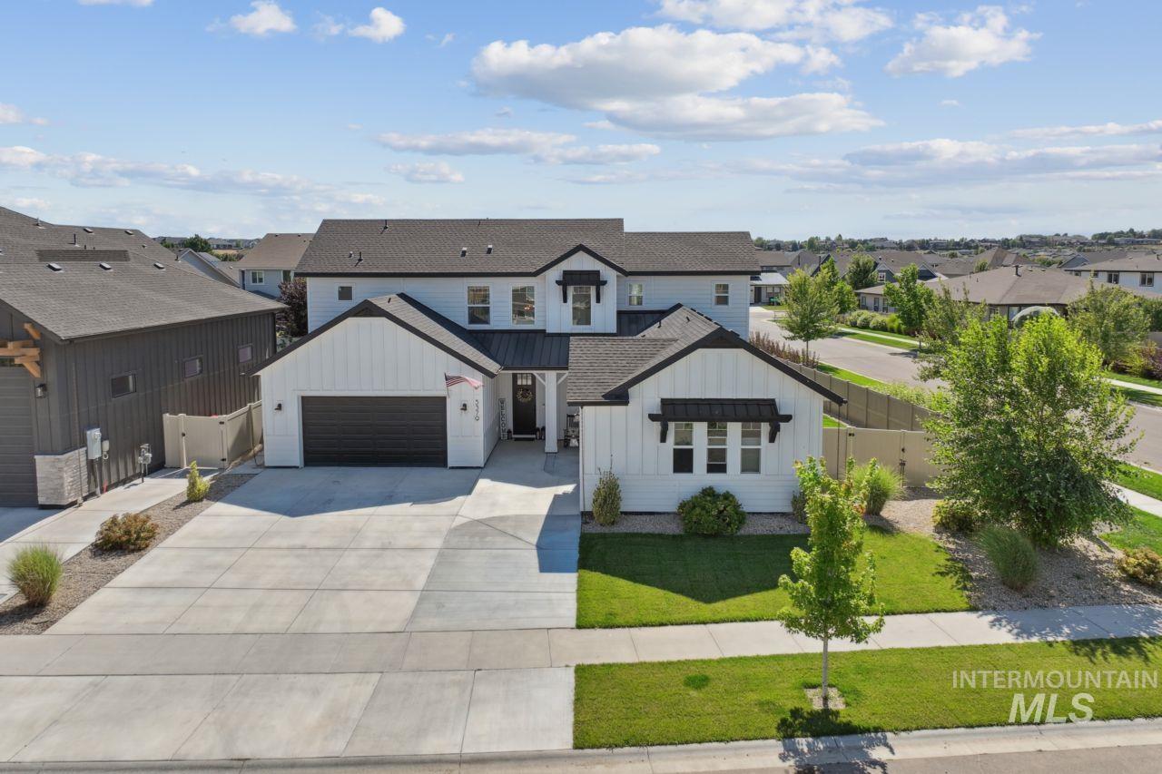Modern farmhouse style home featuring board and batten siding, a residential view, concrete driveway, a gate, and a shingled roof