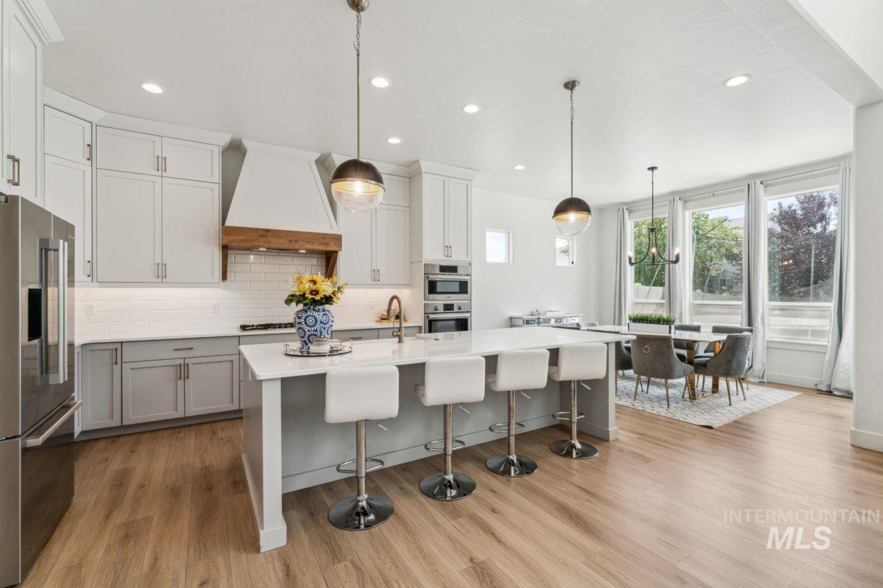 Kitchen featuring stainless steel appliances, tasteful backsplash, custom exhaust hood, light countertops, and a breakfast bar area