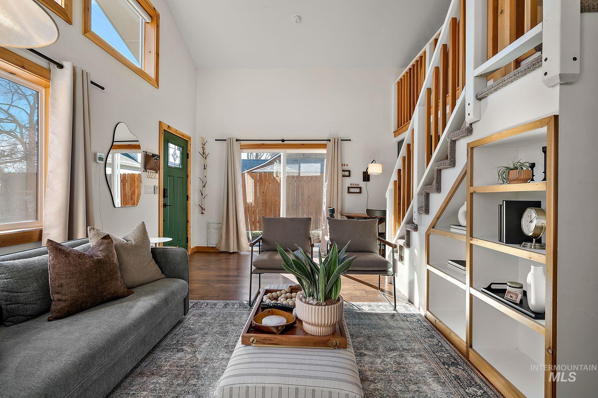 Living room featuring plenty of natural light, stairway, a high ceiling, and wood finished floors