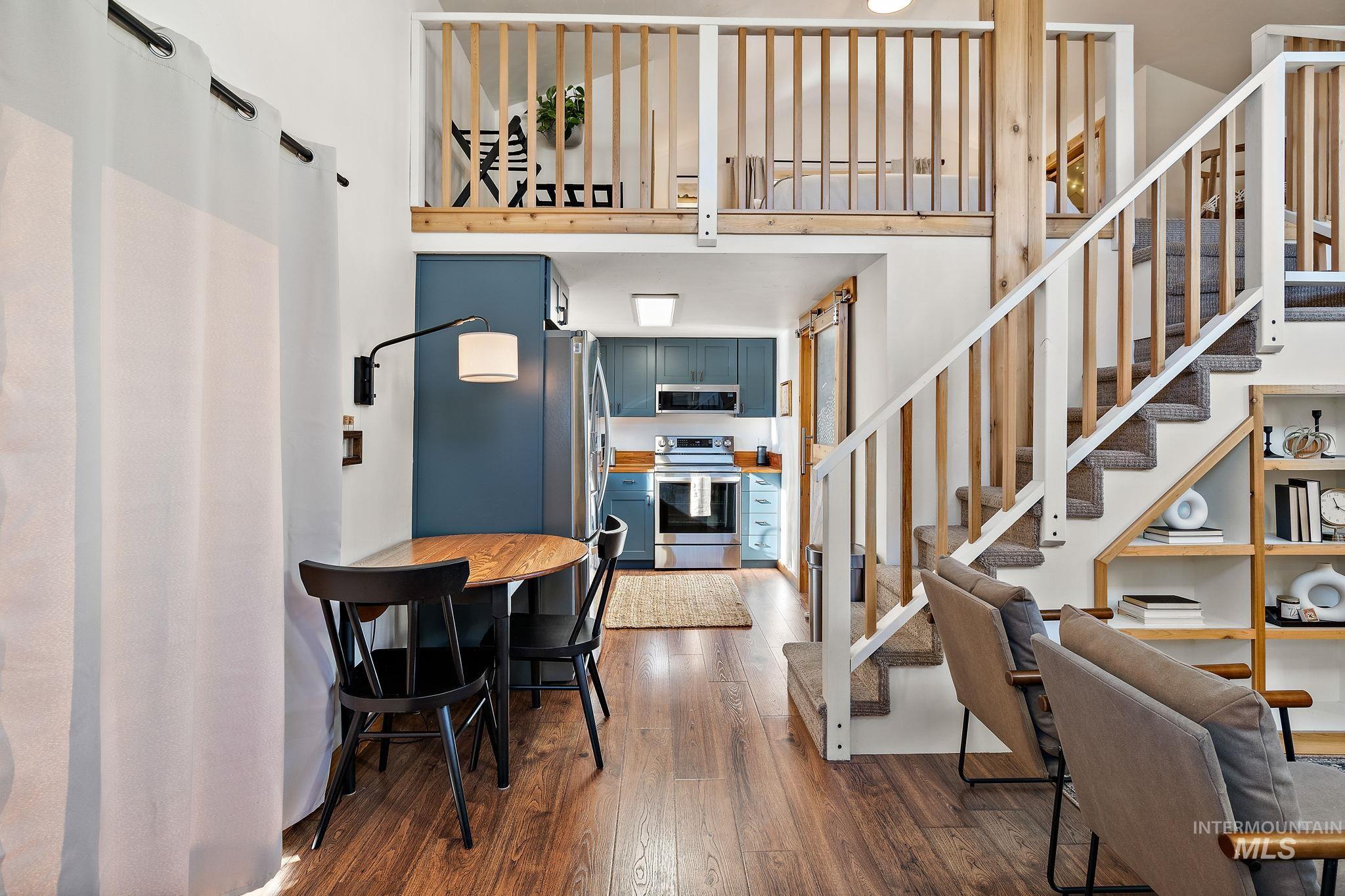 Dining space with dark wood-style flooring, a towering ceiling, and stairway
