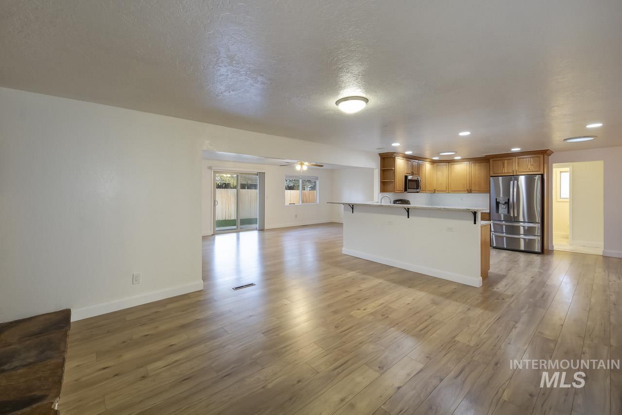 Unfurnished living room with ceiling fan, light wood-style floors, recessed lighting, and a textured ceiling