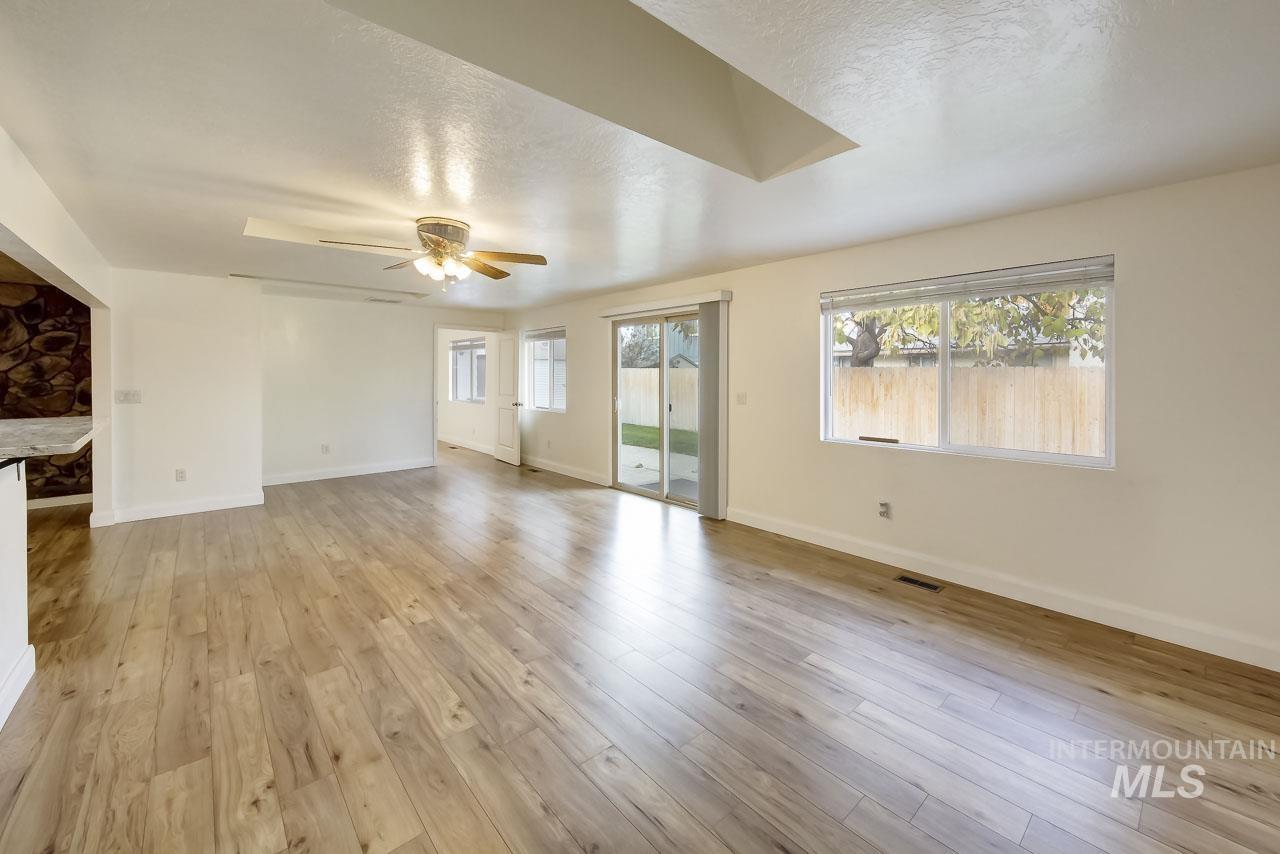 Unfurnished living room with healthy amount of natural light, a textured ceiling, light wood-style flooring, and a ceiling fan