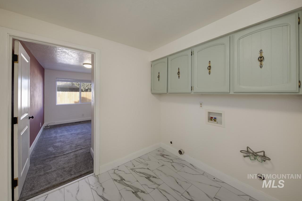 Laundry area featuring light marble finish flooring, hookup for a washing machine, and cabinet space