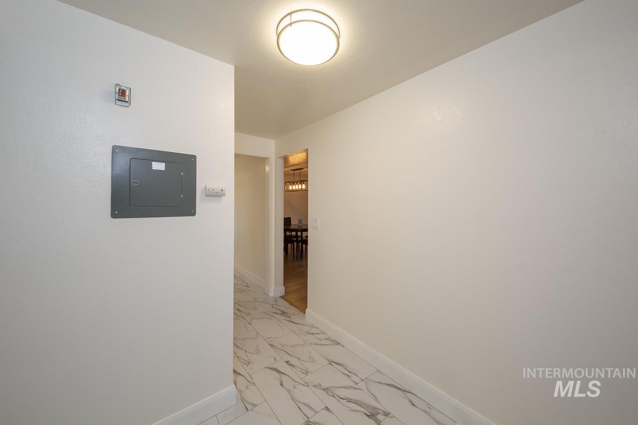 Hall with light marble finish flooring and electric panel