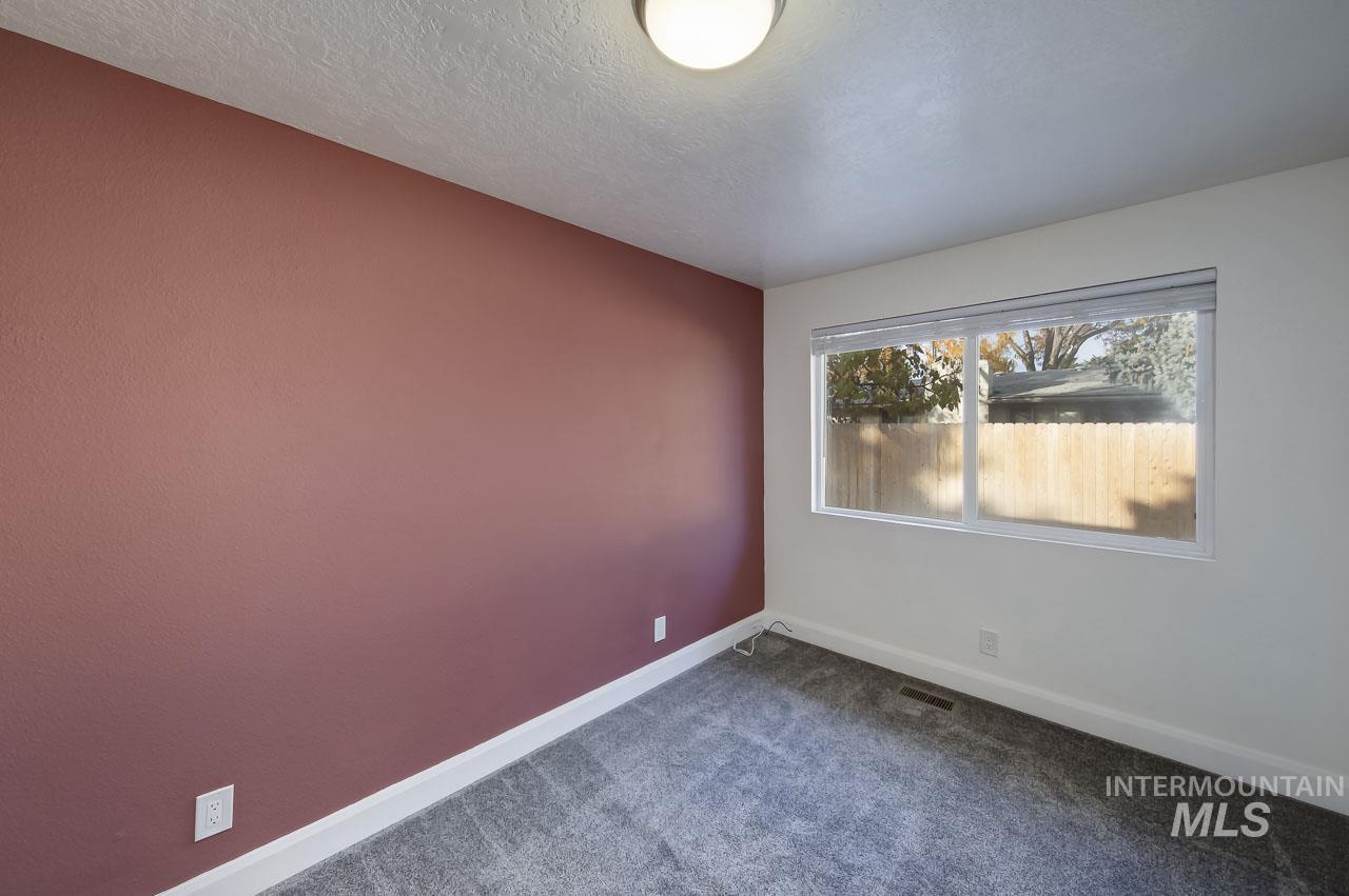 Unfurnished room featuring dark colored carpet and a textured ceiling