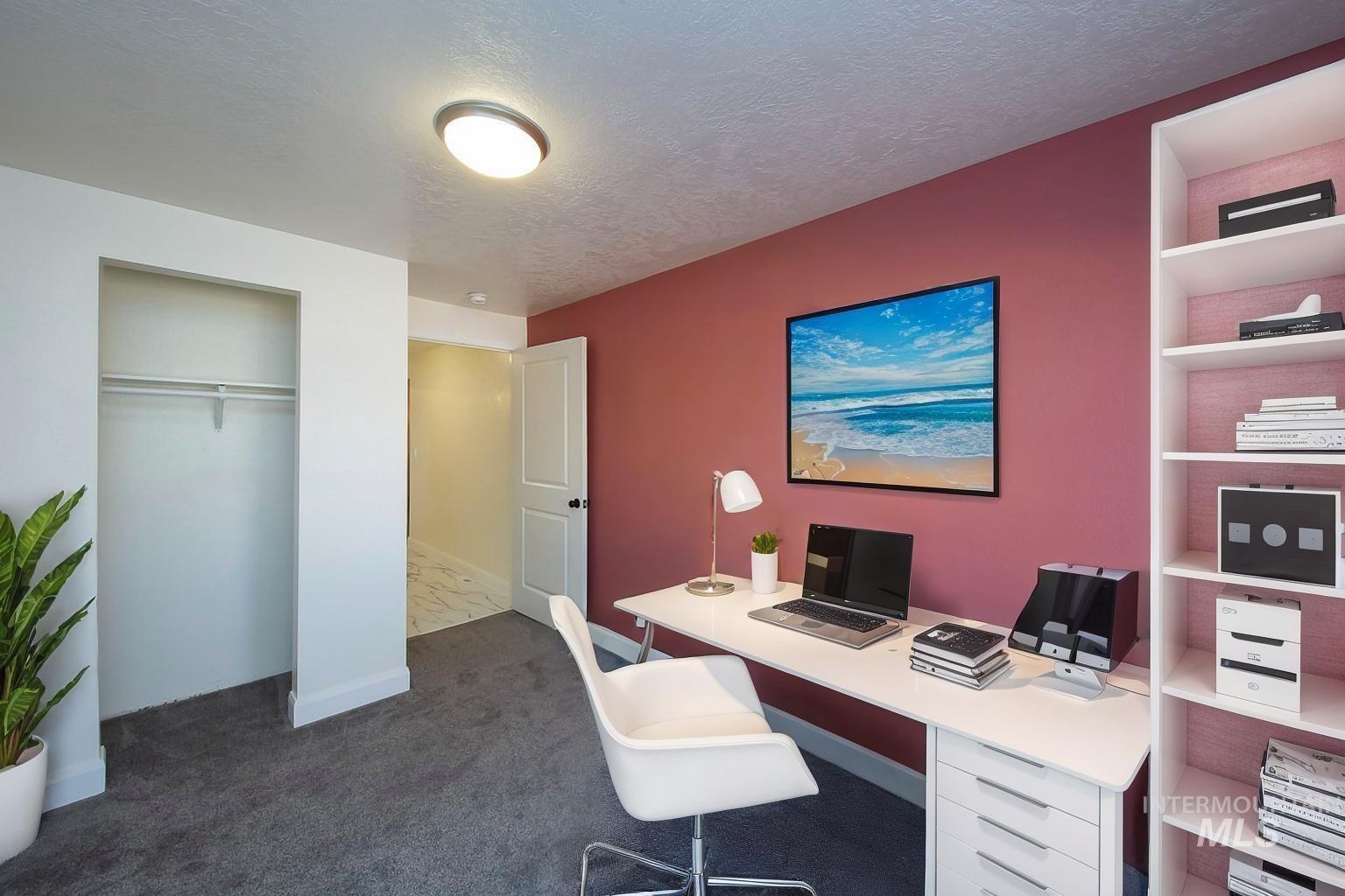 Home office with a textured ceiling and dark carpet