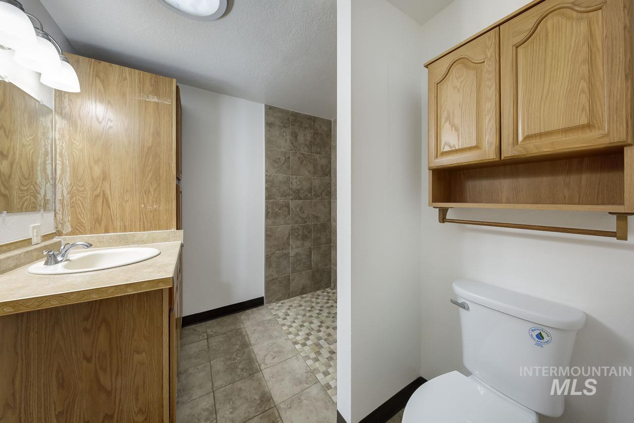 Bathroom with vanity, light tile patterned flooring, tiled shower, and a textured ceiling