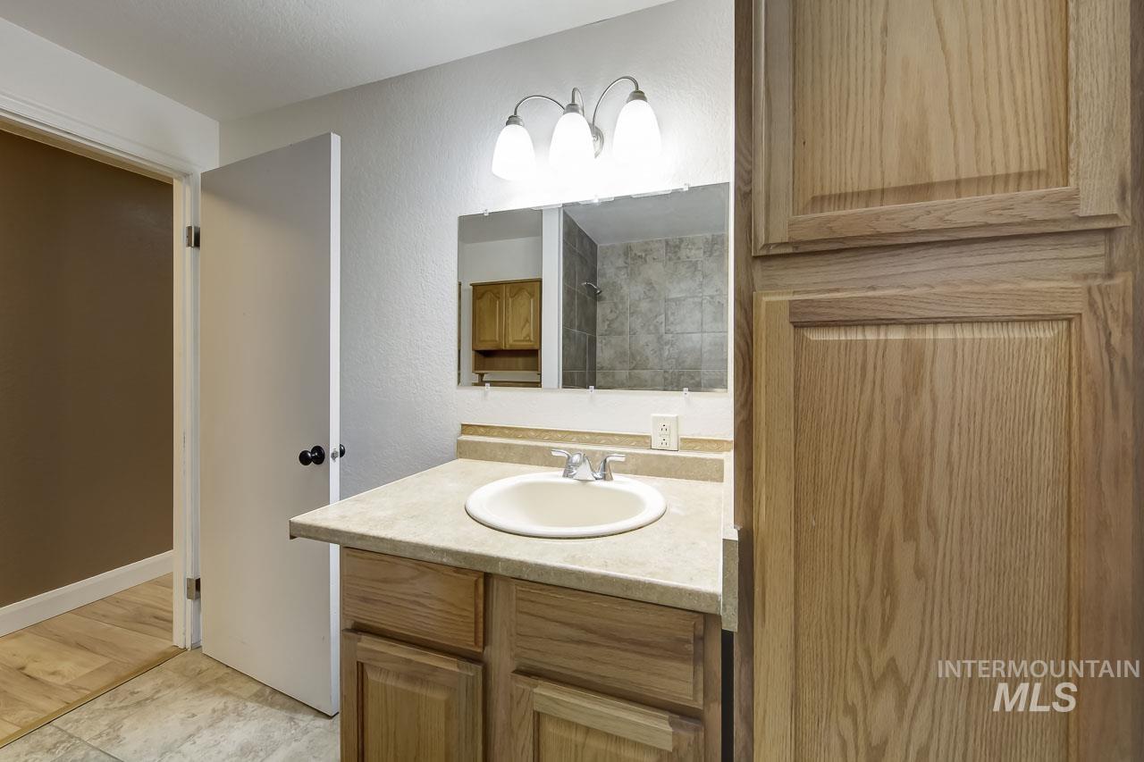Full bath featuring vanity, a textured wall, and a tile shower