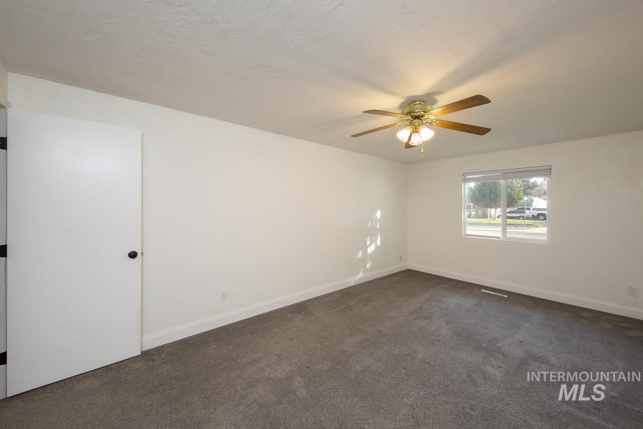 Empty room featuring dark colored carpet and ceiling fan