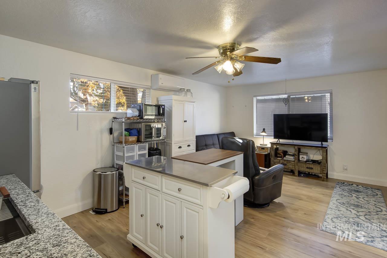 Kitchen featuring freestanding refrigerator, light wood finished floors, a ceiling fan, open floor plan, and white cabinets