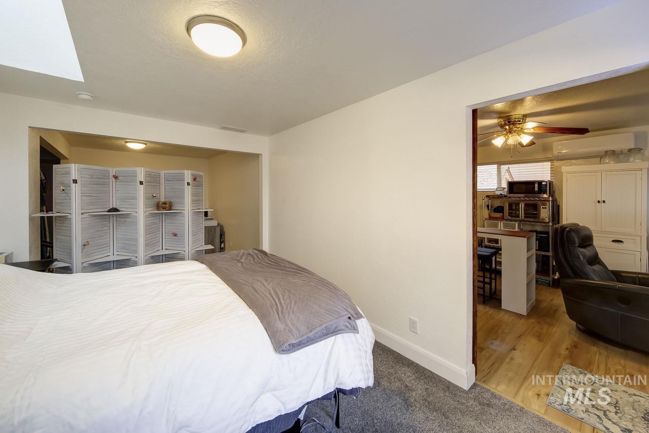 Bedroom with wood finished floors, a wall mounted AC, an office area, a ceiling fan, and a textured ceiling