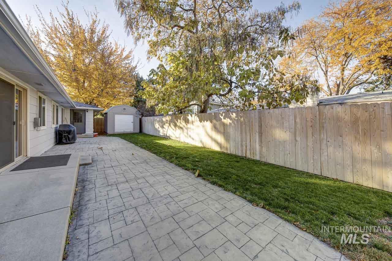 Fenced backyard featuring a patio, an outdoor structure, and grilling area