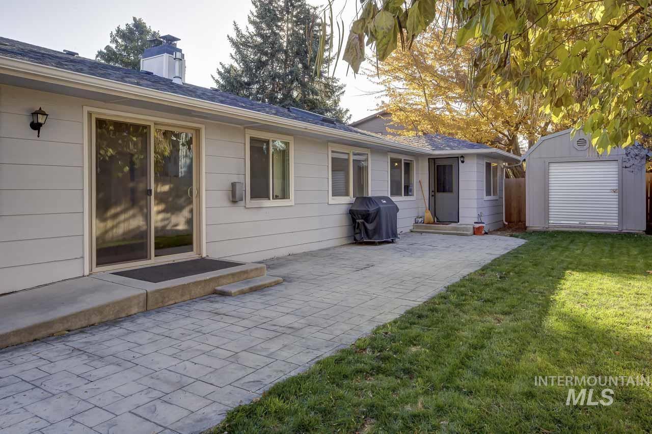 Back of house featuring a yard, an outdoor structure, a patio, and a chimney