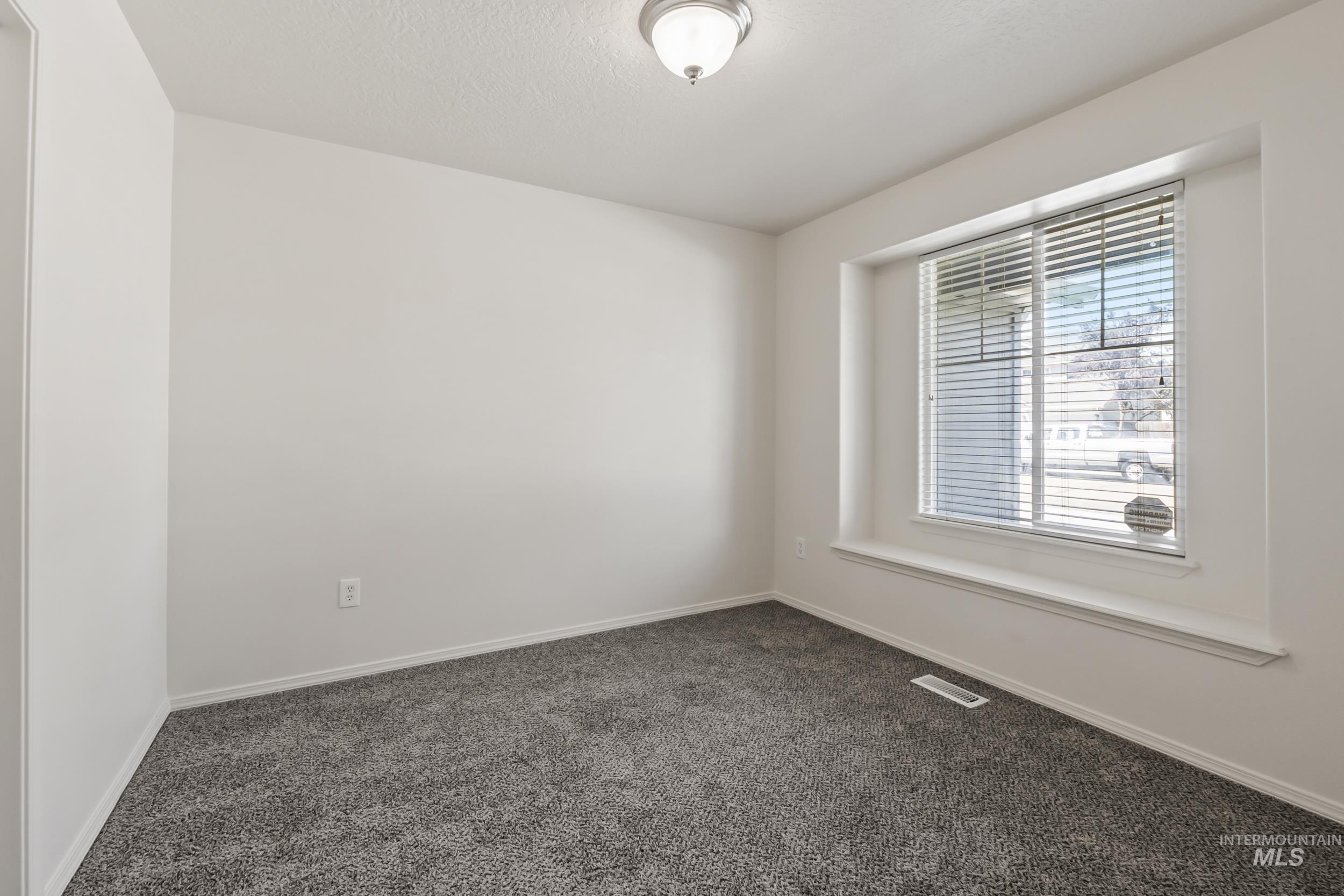 Empty room featuring dark carpet and a textured ceiling