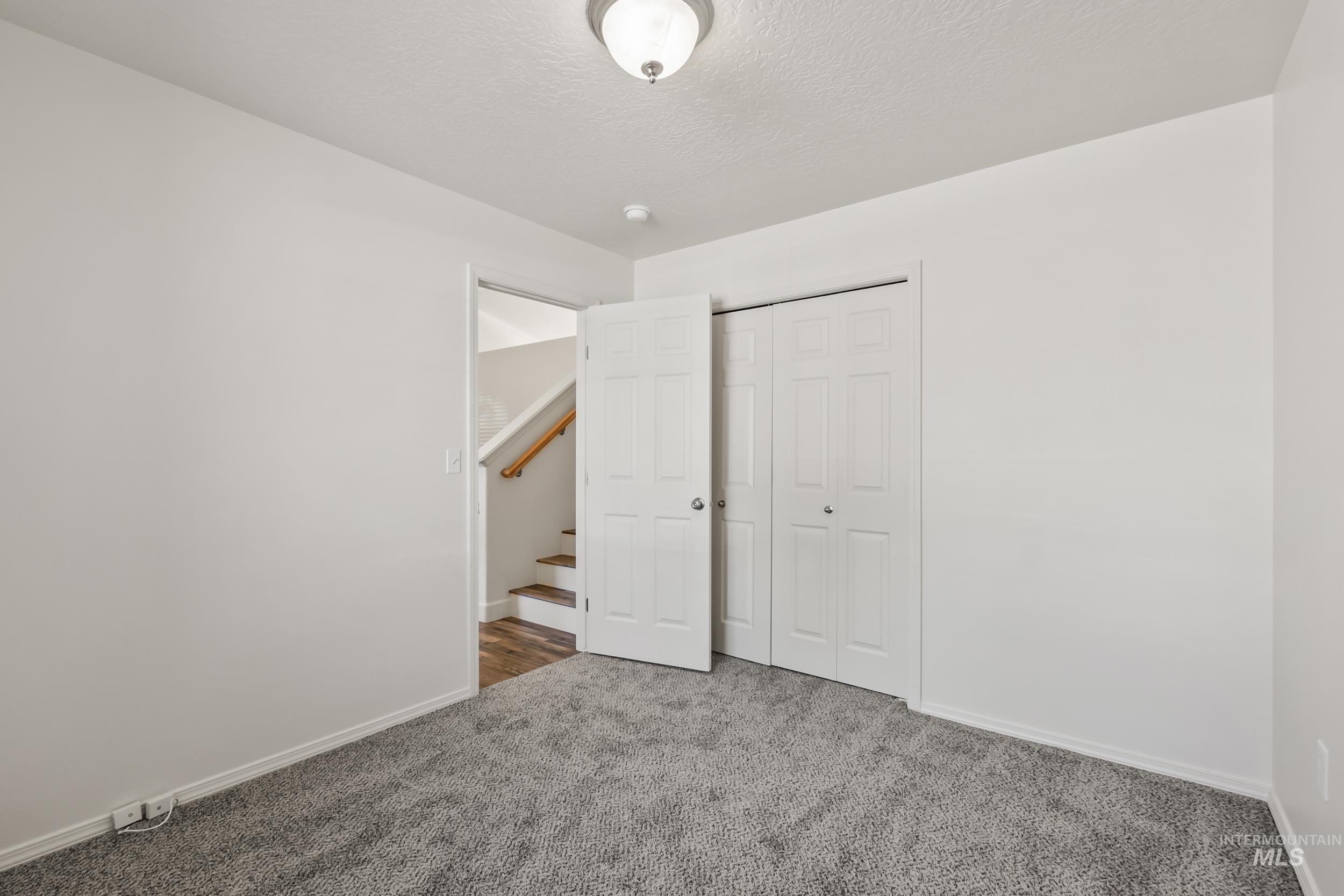 Unfurnished bedroom with a closet, carpet floors, and a textured ceiling
