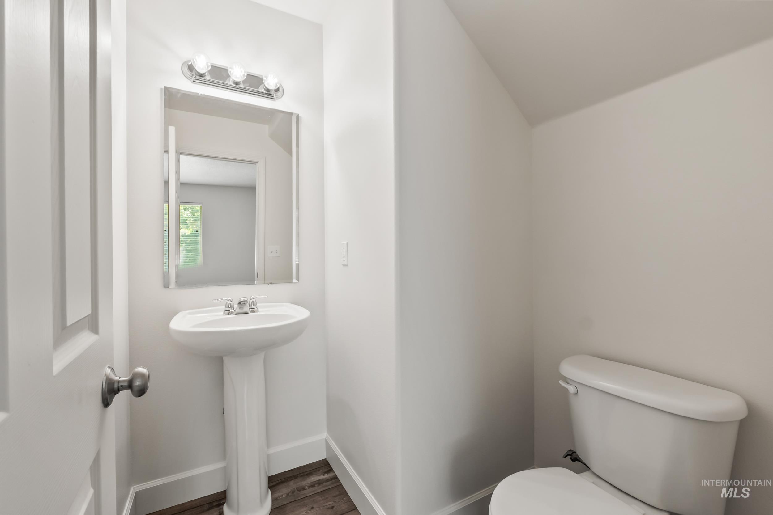 Half bath with toilet and wood finished floors