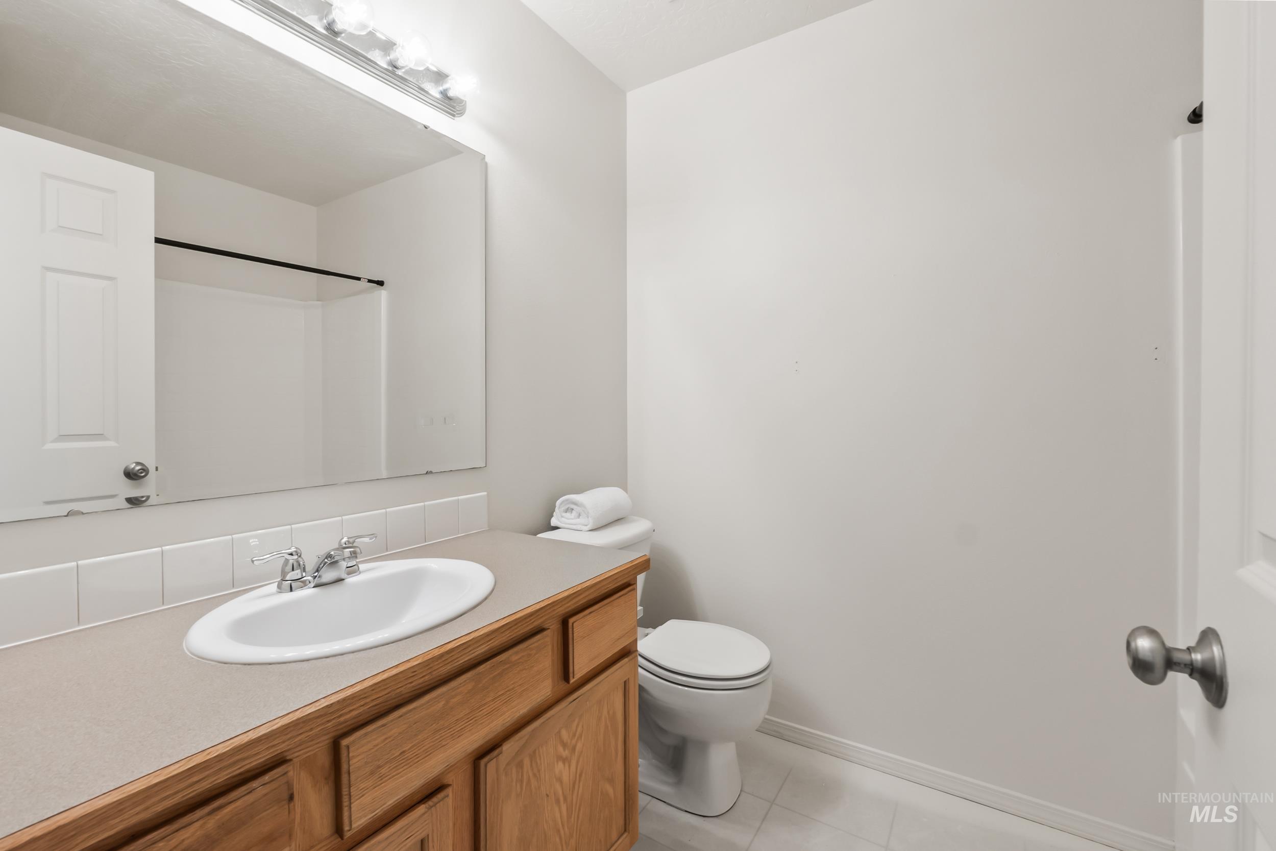 Full bathroom with vanity, light tile patterned flooring, and a shower