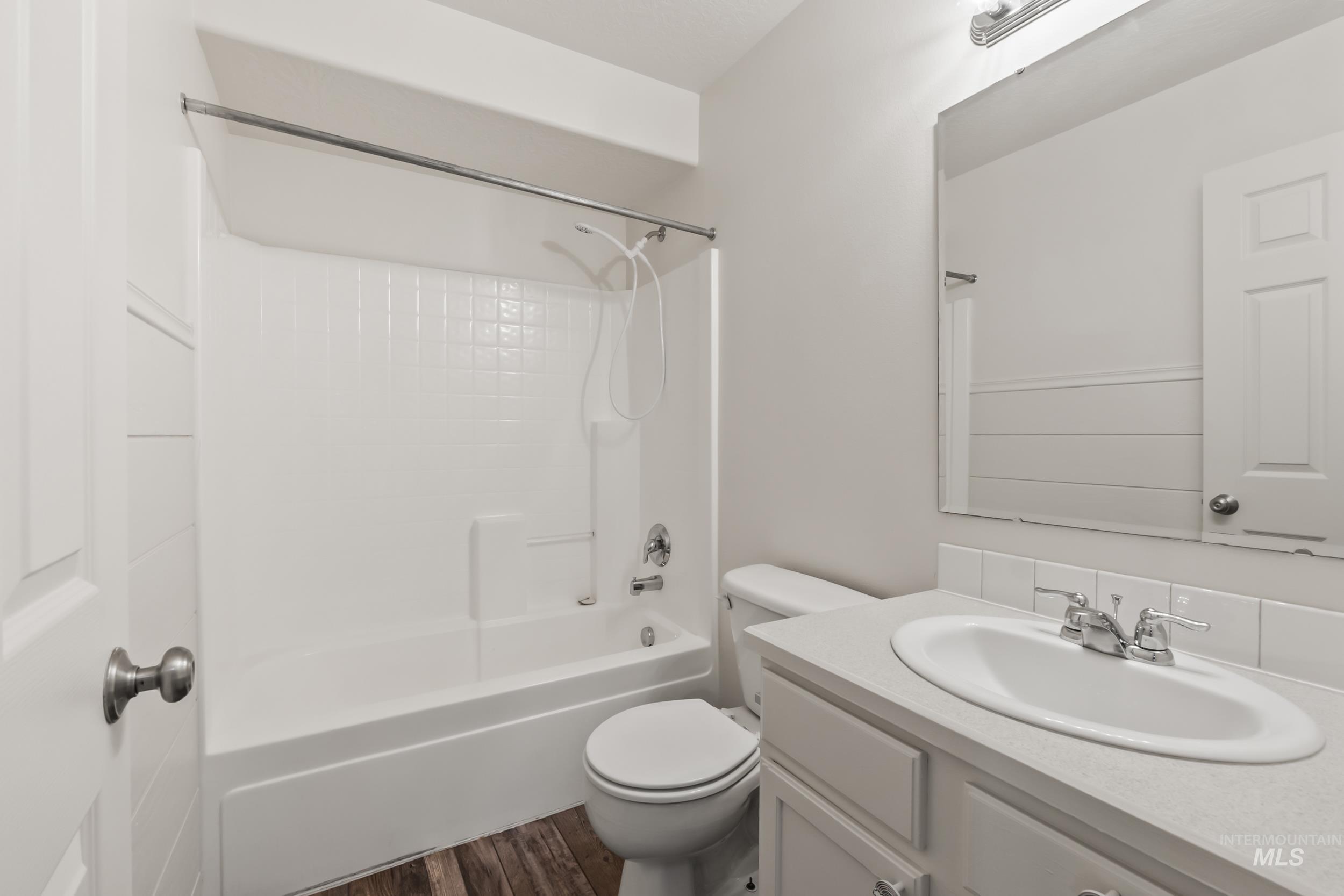Bathroom with washtub / shower combination, vanity, and dark wood-type flooring