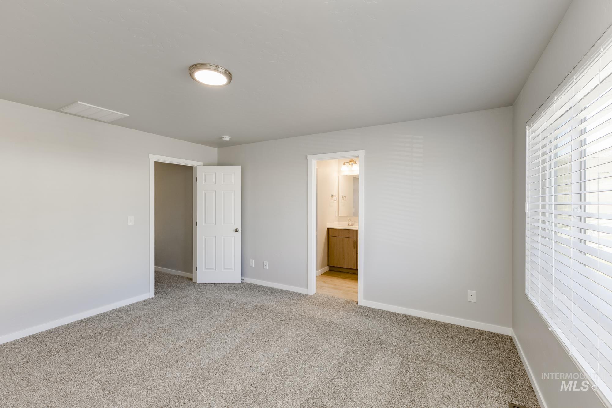 Unfurnished bedroom featuring light colored carpet and connected bathroom