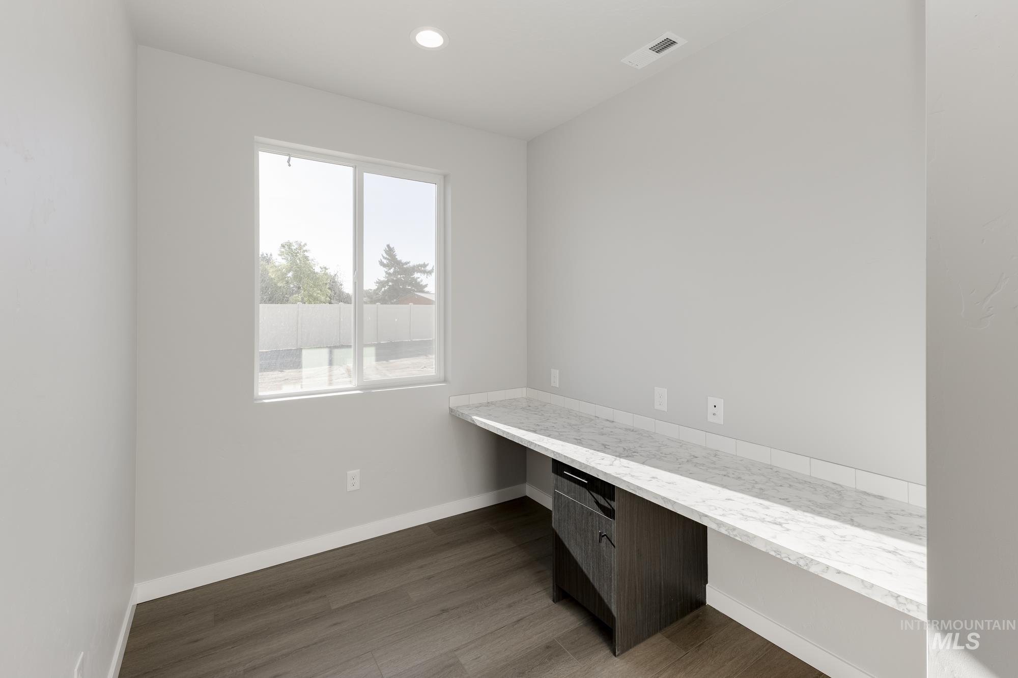 Unfurnished office with built in desk, dark wood-type flooring, and recessed lighting