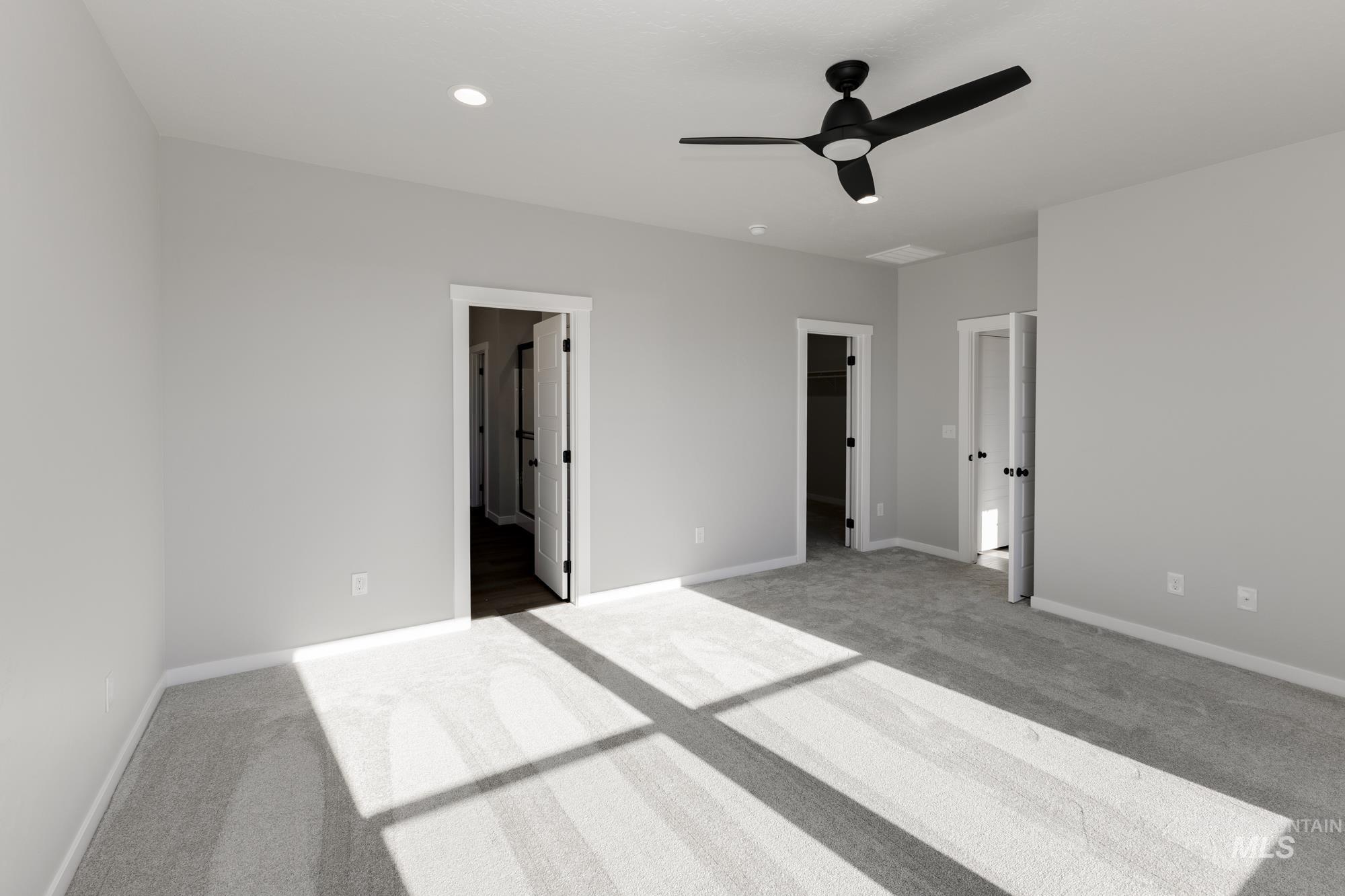 Unfurnished bedroom with carpet flooring, a walk in closet, connected bathroom, a ceiling fan, and recessed lighting