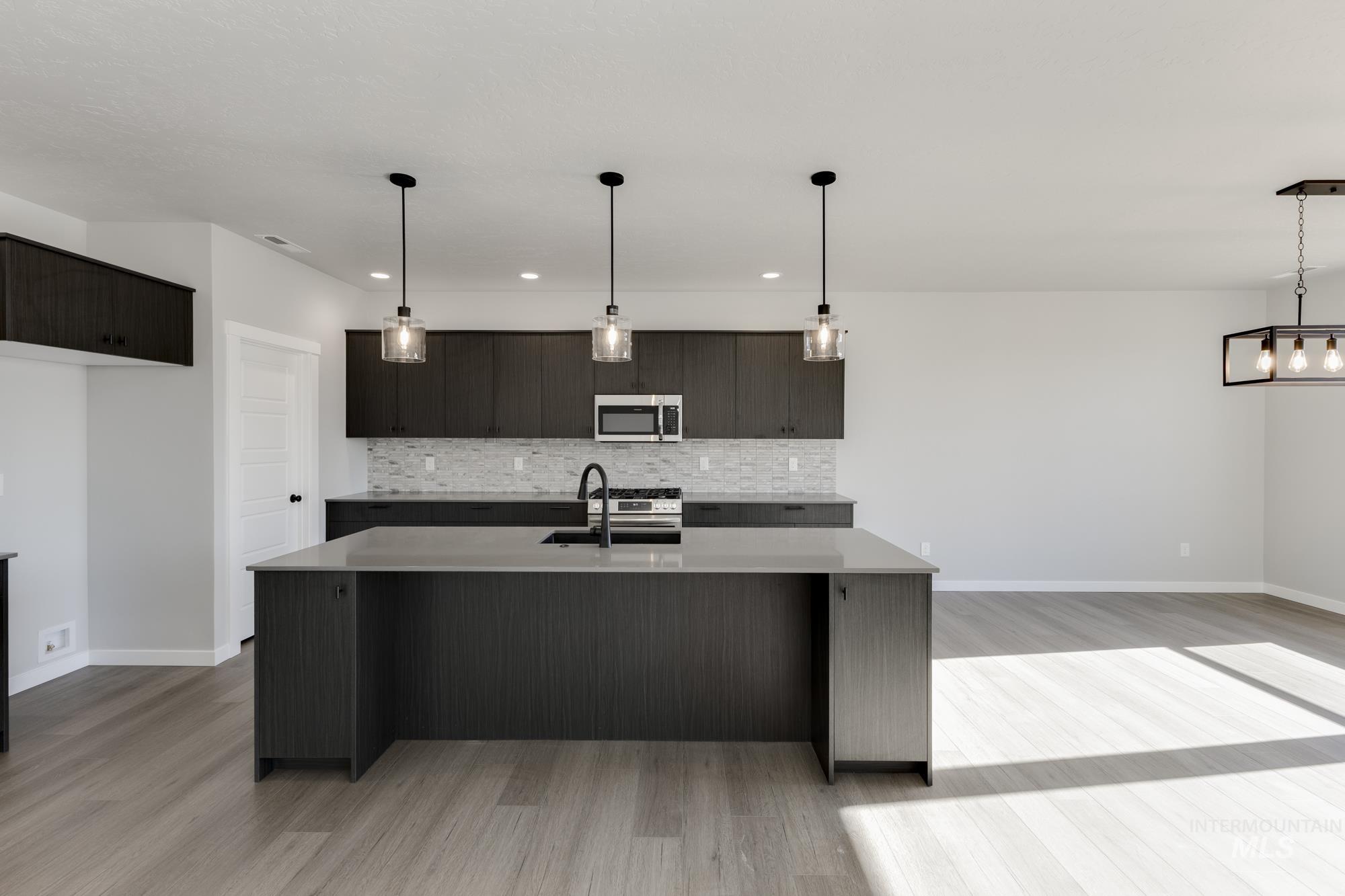 Kitchen with decorative backsplash, pendant lighting, an island with sink, modern cabinets, and recessed lighting