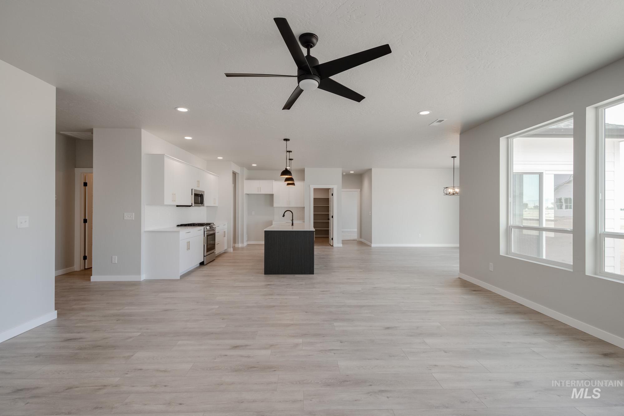 Unfurnished living room featuring light wood-style flooring, ceiling fan, and recessed lighting