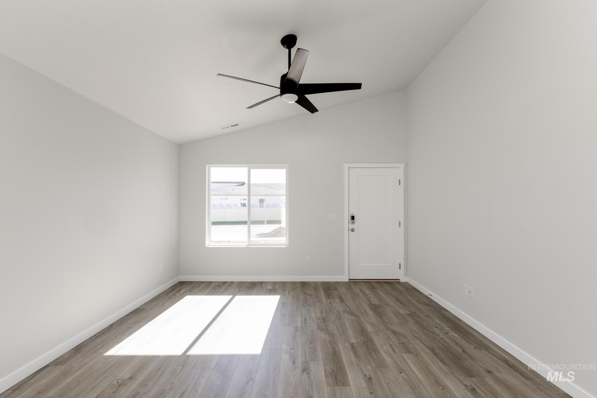 Spare room featuring wood finished floors, ceiling fan, and high vaulted ceiling