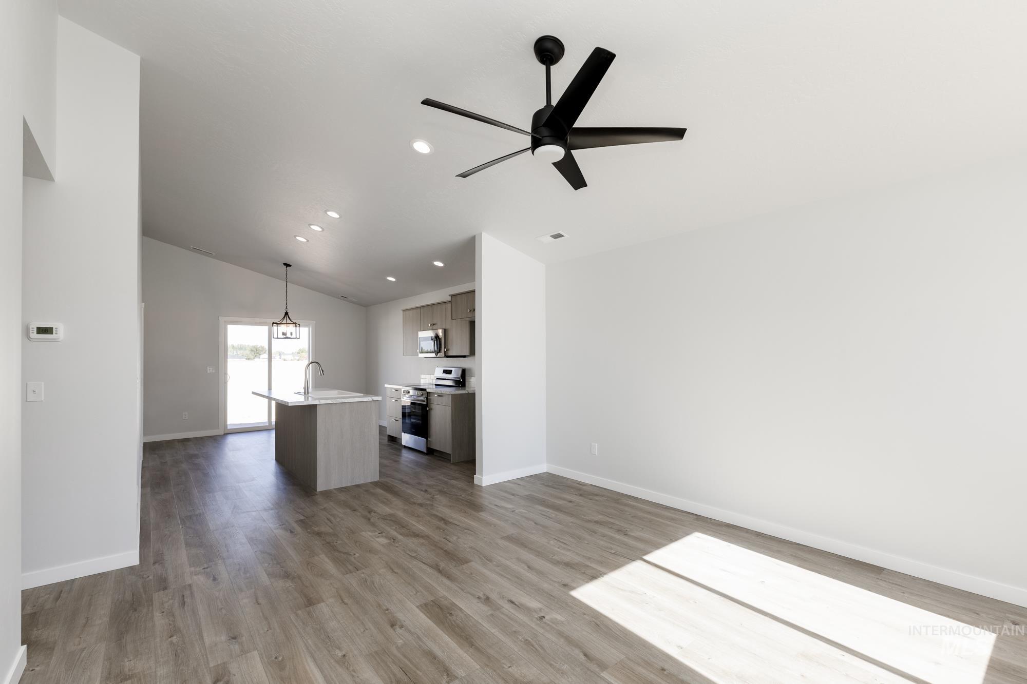 Unfurnished living room featuring dark wood finished floors, lofted ceiling, ceiling fan, and recessed lighting