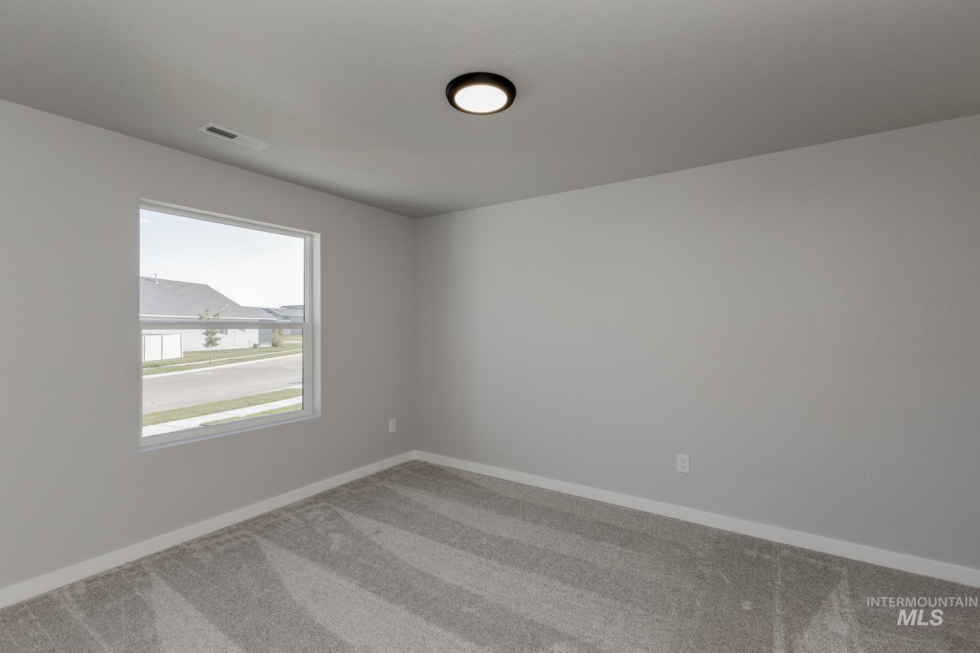 Carpeted spare room featuring baseboards