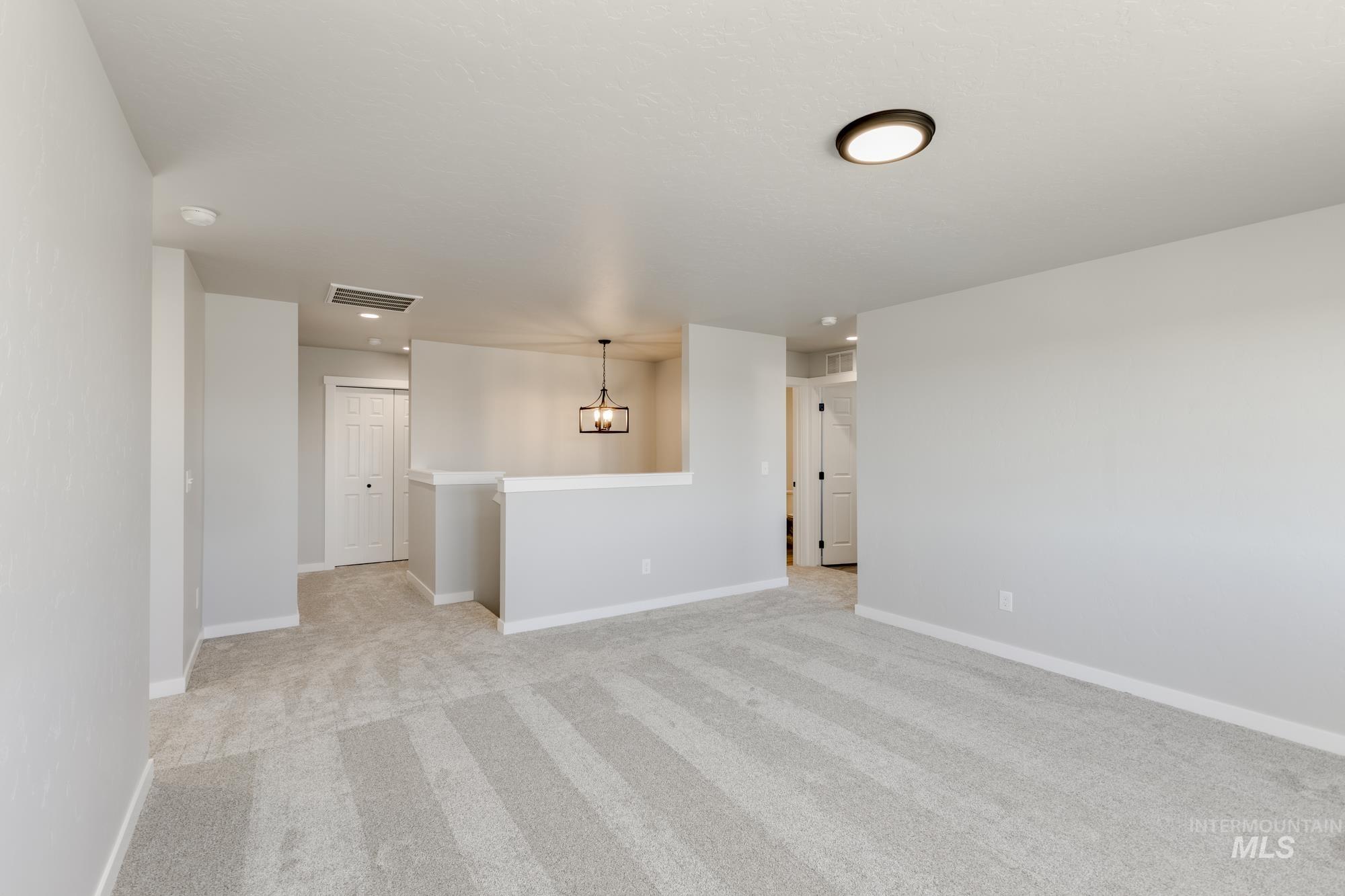 Unfurnished room featuring light carpet and a chandelier