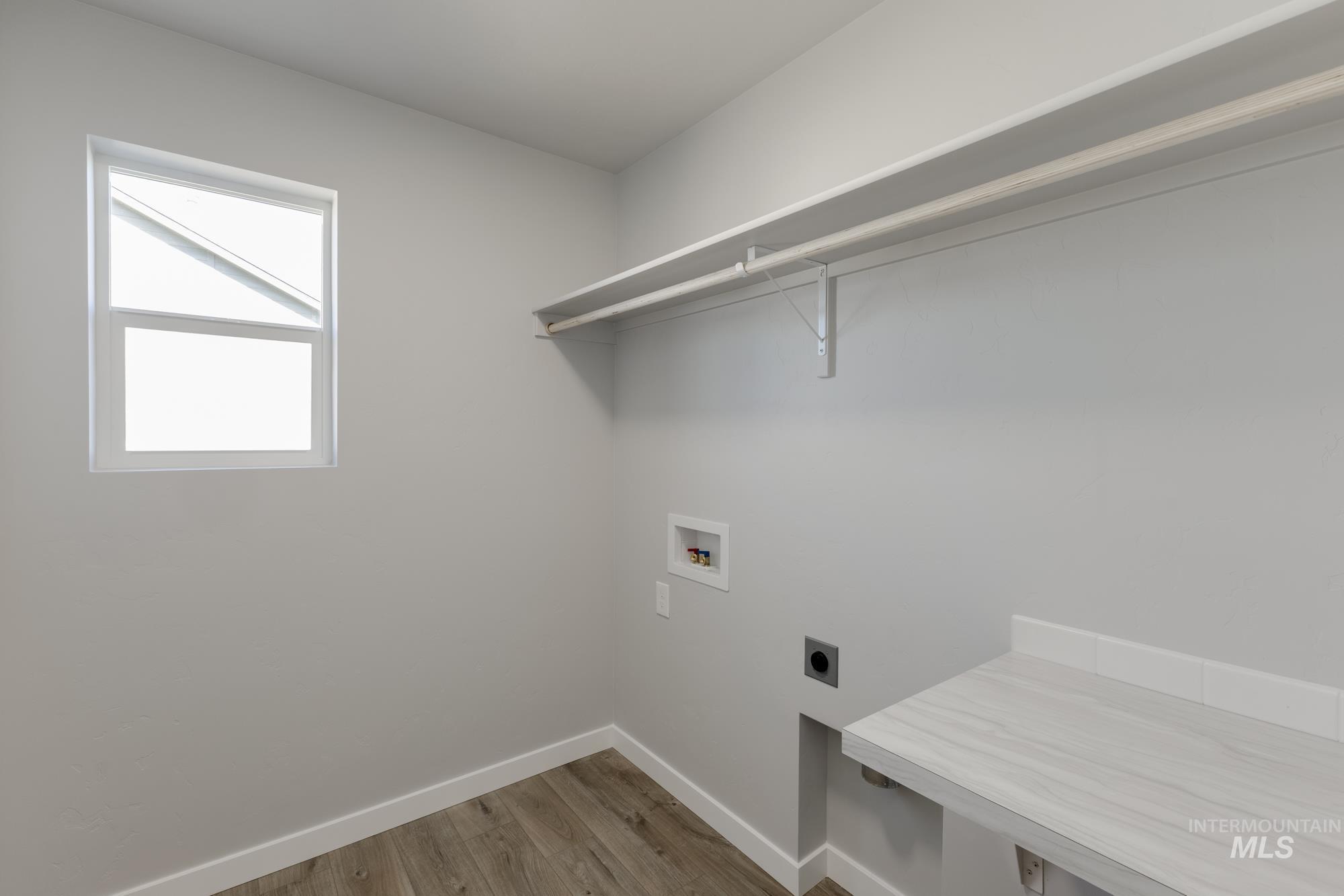 Washroom with light wood-type flooring, hookup for a washing machine, and hookup for an electric dryer