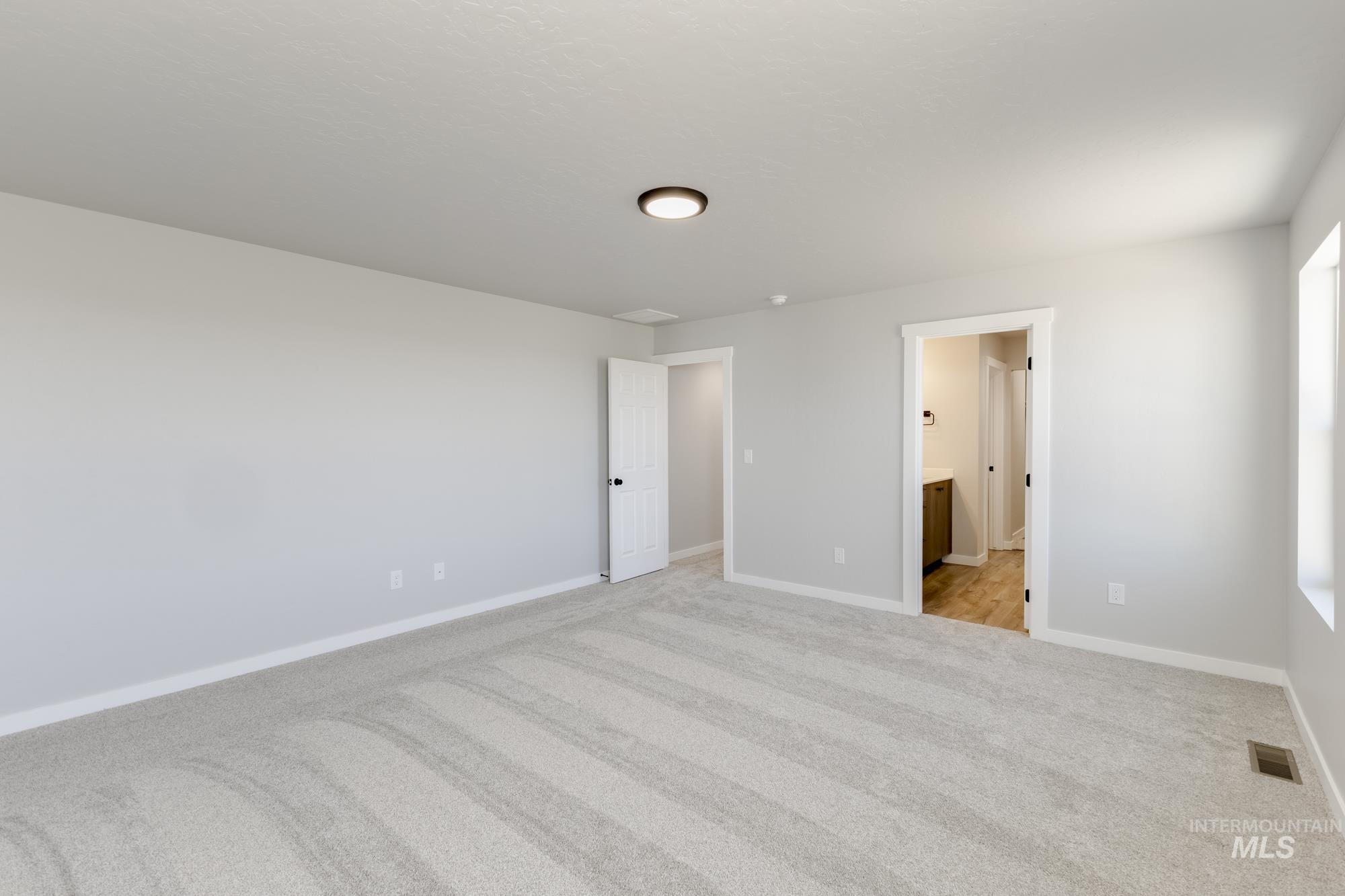 Unfurnished bedroom featuring light colored carpet and ensuite bathroom