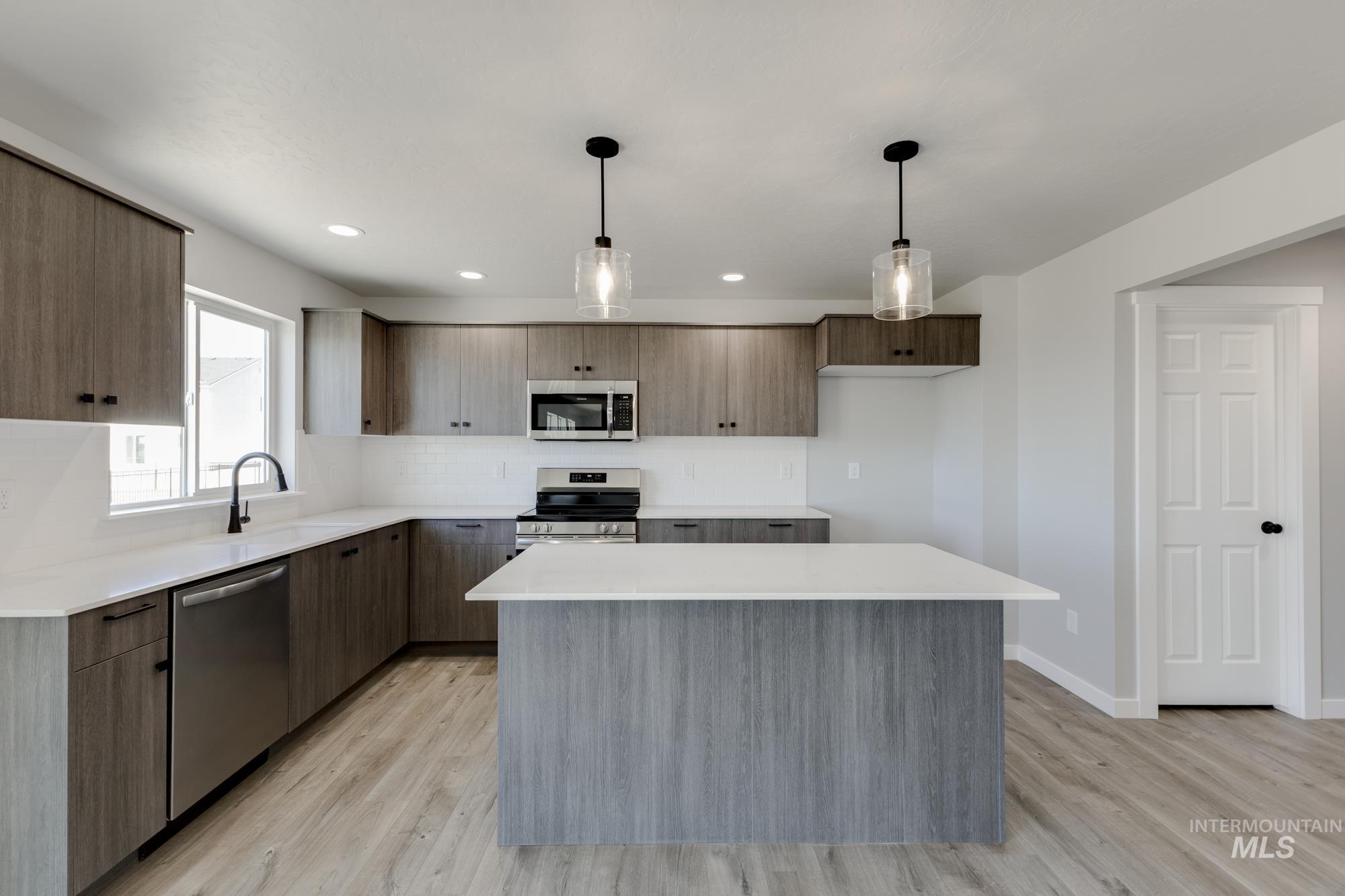 Kitchen featuring decorative light fixtures, a kitchen island, appliances with stainless steel finishes, modern cabinets, and recessed lighting