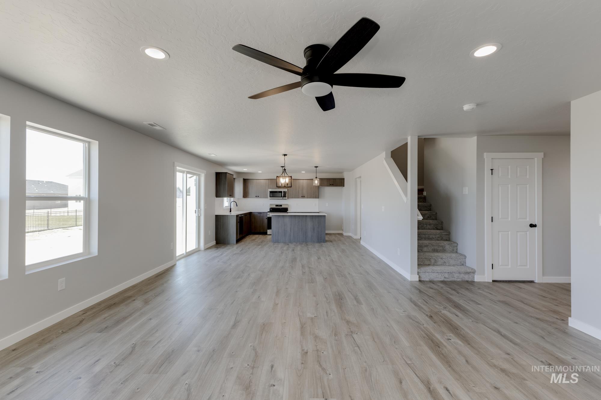 Unfurnished living room featuring stairway, light wood-type flooring, a ceiling fan, and recessed lighting