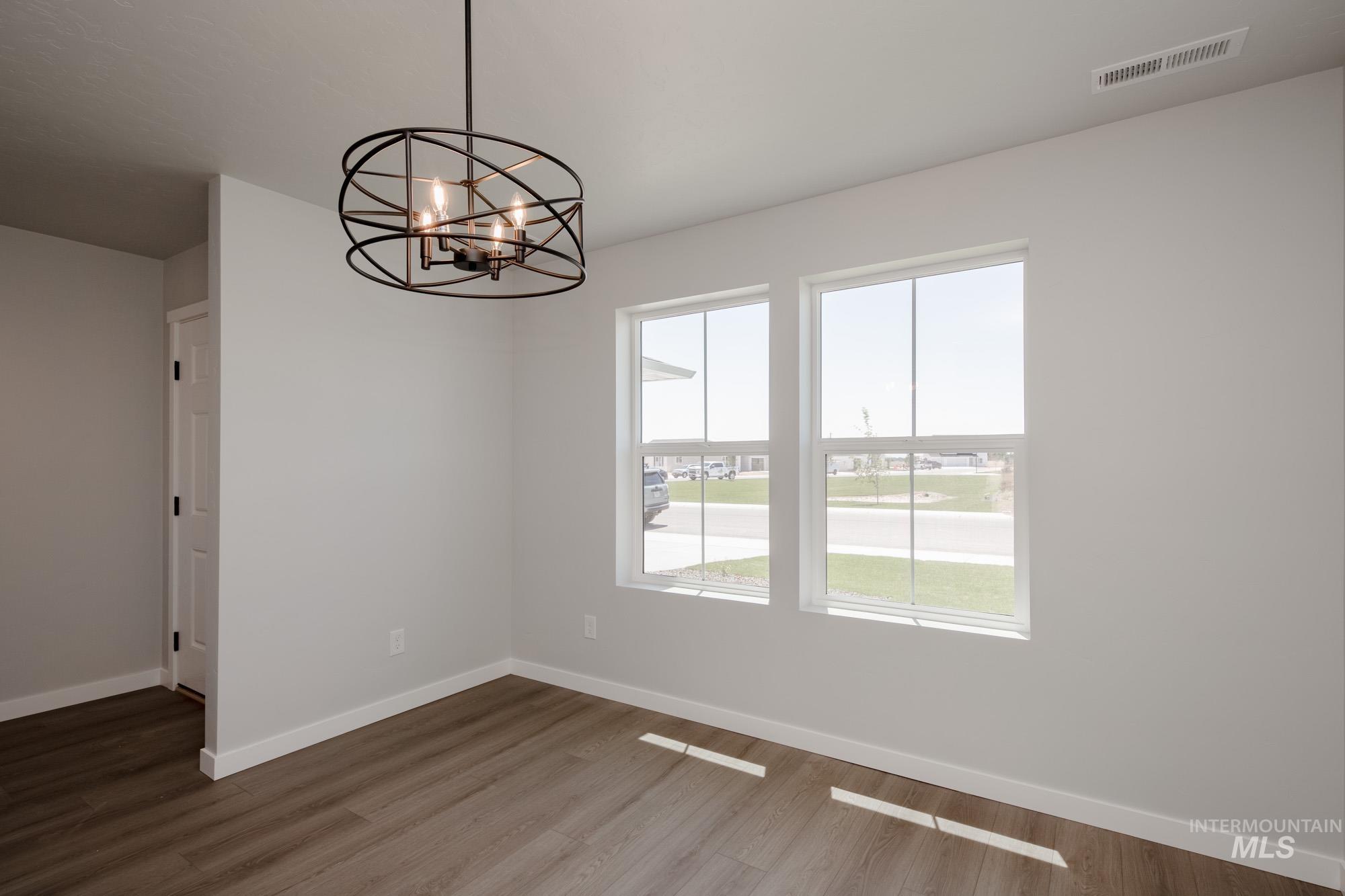 Unfurnished dining area featuring dark wood-style flooring and a chandelier