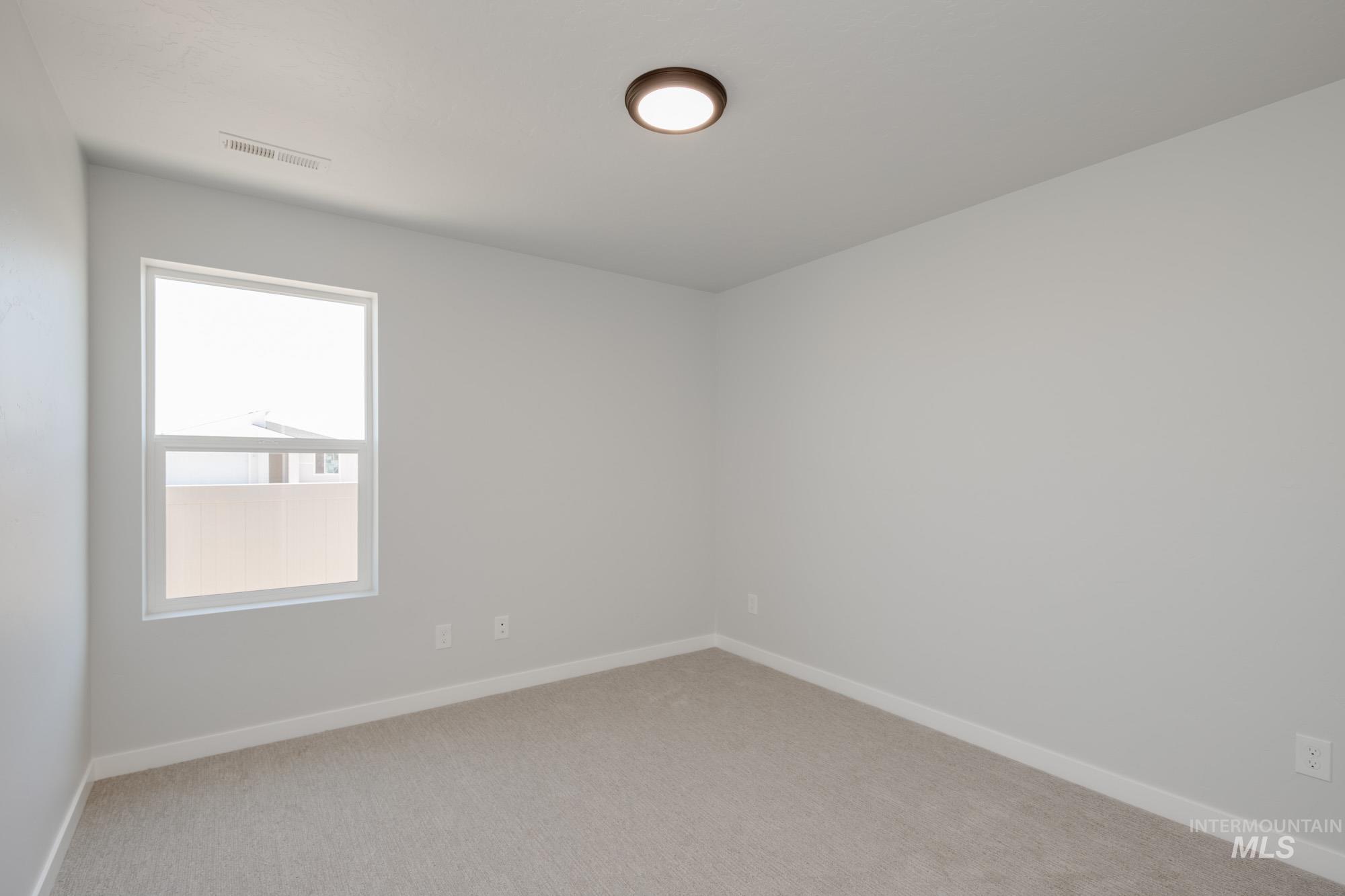 Spare room with baseboards and light carpet