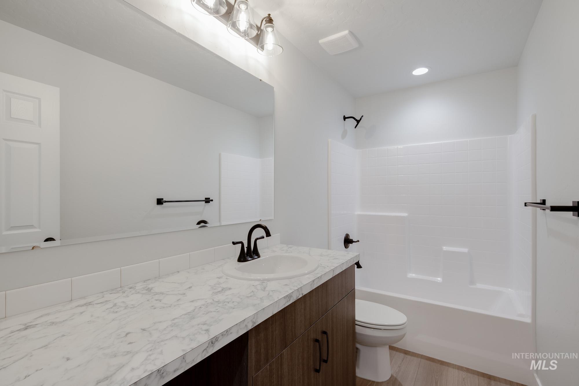 Full bathroom with vanity, shower / washtub combination, light wood-style flooring, and recessed lighting